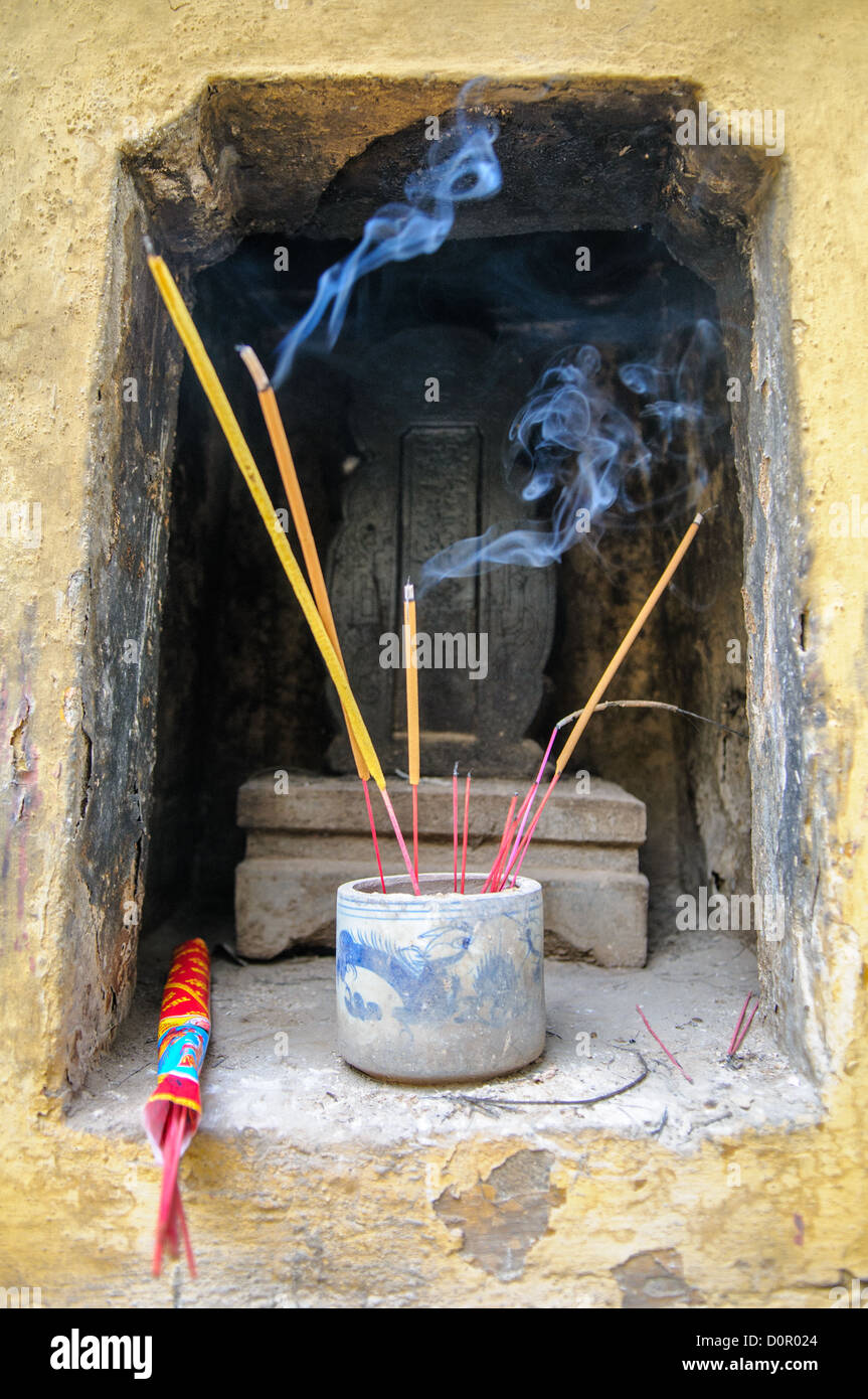 HANOI, Vietnam - bastoncini di incenso brucianti si trovano in un santuario della Pagoda Tran Quoc, sull'isolotto Golden Fish del Lago Occidentale. Questa tradizionale offerta buddhista continua in uno dei templi più antichi del Vietnam, trasferito nel suo sito attuale nel 1615. Il santuario dell'incenso funge da punto focale per le pratiche devozionali all'interno del complesso del tempio. Foto Stock