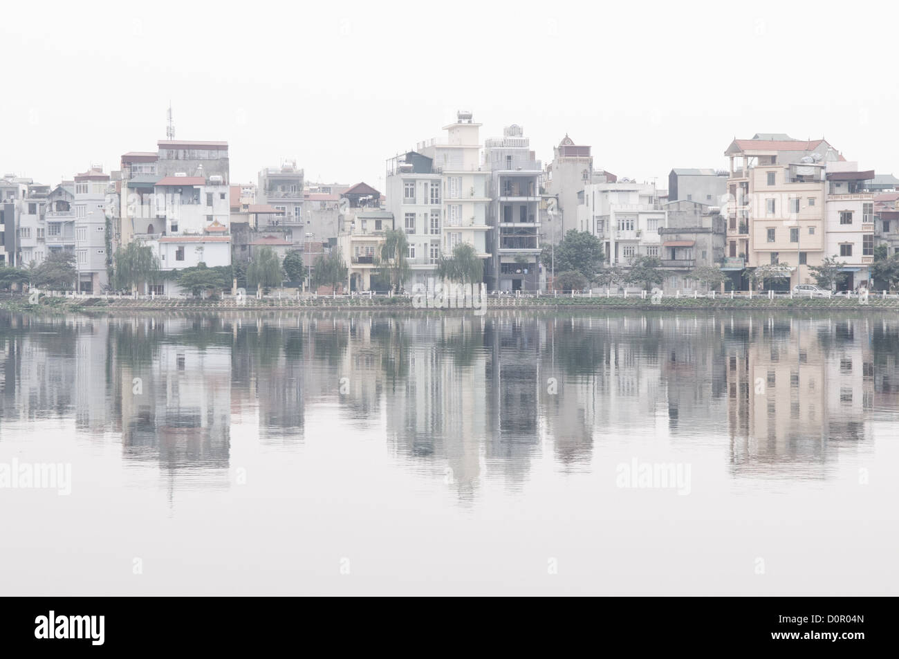 HANOI, Vietnam - Edifici sulla riva si riflettono sulla superficie speculare del West Lake (Ho Tay) ad Hanoi, Vietnam, su un vago giorno. Foto Stock