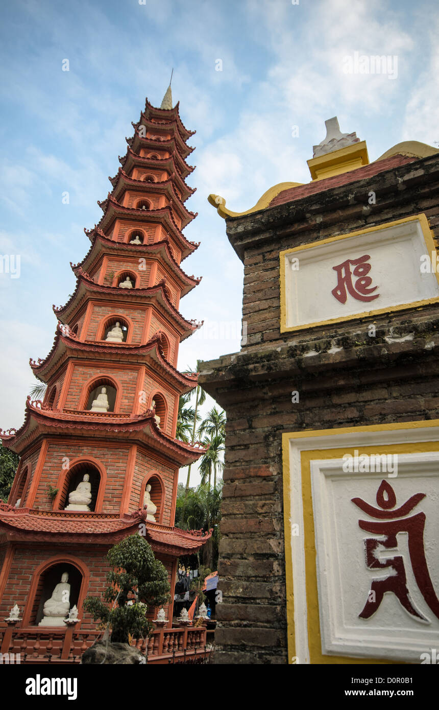 HANOI, Vietnam: Il cancello d'ingresso e la torre della Pagoda Tran Quoc si trovano in posizione dominante sull'isolotto Golden Fish del Lago Occidentale. Il complesso del tempio, trasferito in questo sito nel 1615, presenta elementi architettonici tradizionali buddisti vietnamiti. Queste strutture rappresentano il duraturo patrimonio architettonico di uno dei templi buddisti più antichi del Vietnam. Foto Stock