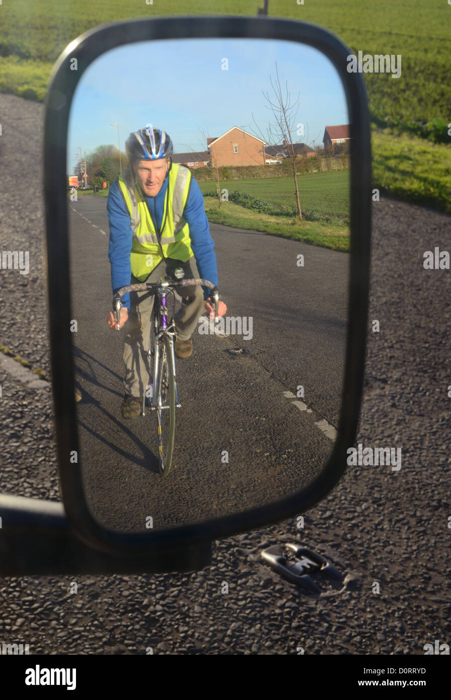 Ciclista di indossare indumenti ad elevata visibilità in refelected parafango del veicolo specchio sulla strada vicino a Leeds Regno Unito Foto Stock