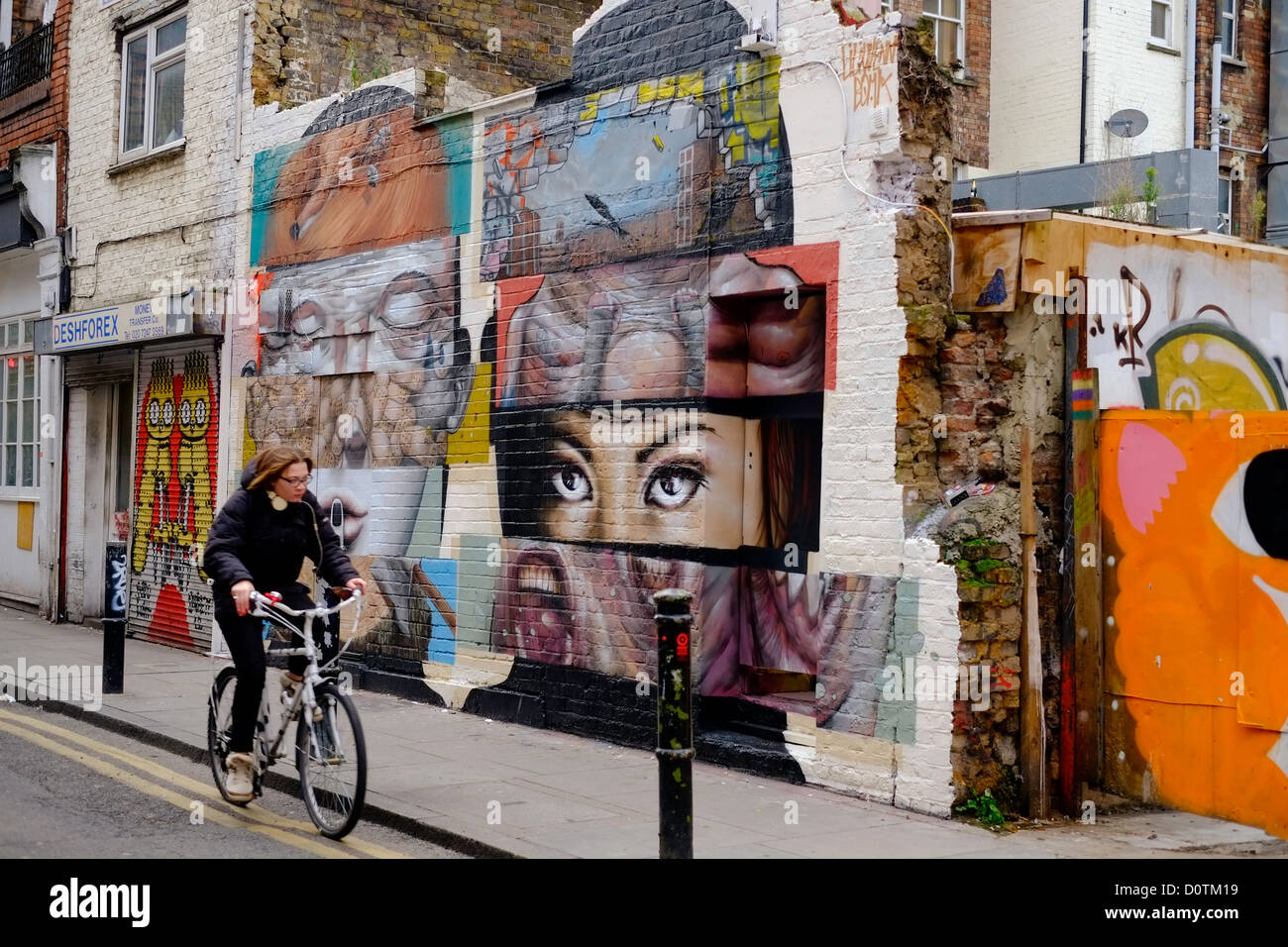 Donna Bicicletta Equitazione passato arte di strada intorno a Brick Lane London E1 Foto Stock