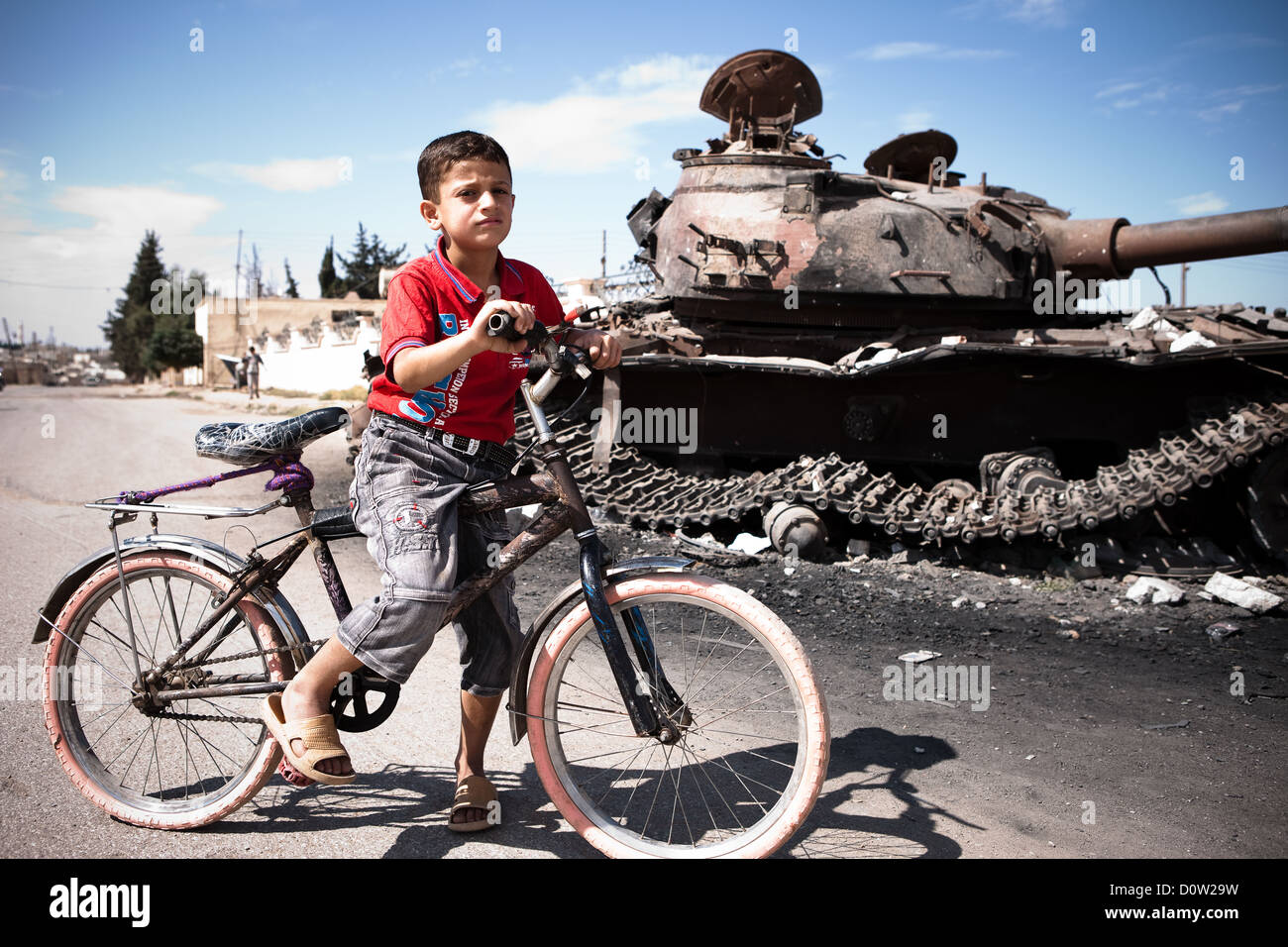 5/10/12. Azaz, Siria. Un giovane ragazzo pause accanto a uno dei molti battaglia serbatoi danneggiati nella città di Azaz. Foto Stock