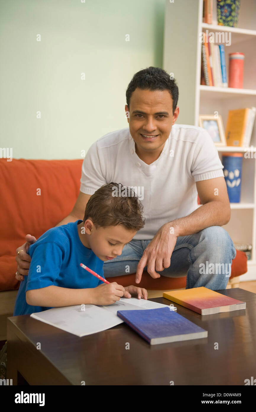 Uomo che assiste il suo figlio nei suoi studi Foto Stock