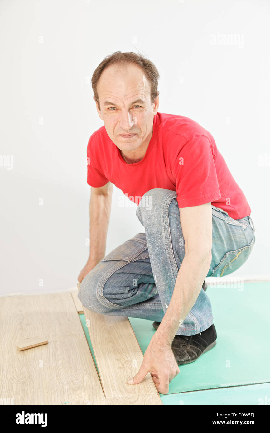 Uomo positivo in rosso installazione di pavimentazione Foto Stock