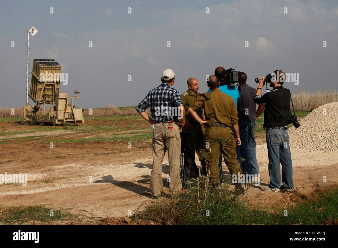 I giornalisti intervistano il maggiore Aryeh Shalikar, portavoce dell'esercito israeliano accanto a una batteria del sistema missilistico di difesa Iron Dome di Israele, progettato per intercettare e distruggere i missili a corto raggio e le conchiglie di artiglieria in arrivo, schierati alla periferia della città meridionale di Ashkelon in Israele Foto Stock