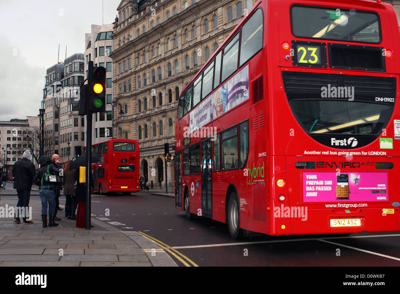 Un rosso London double decker bus passando verde semaforo mentre la gente in attesa di attraversare la strada Foto Stock