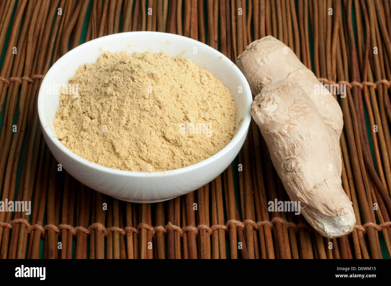 Lo zenzero in polvere in una ciotola e tutto lo zenzero su base di legno Foto Stock