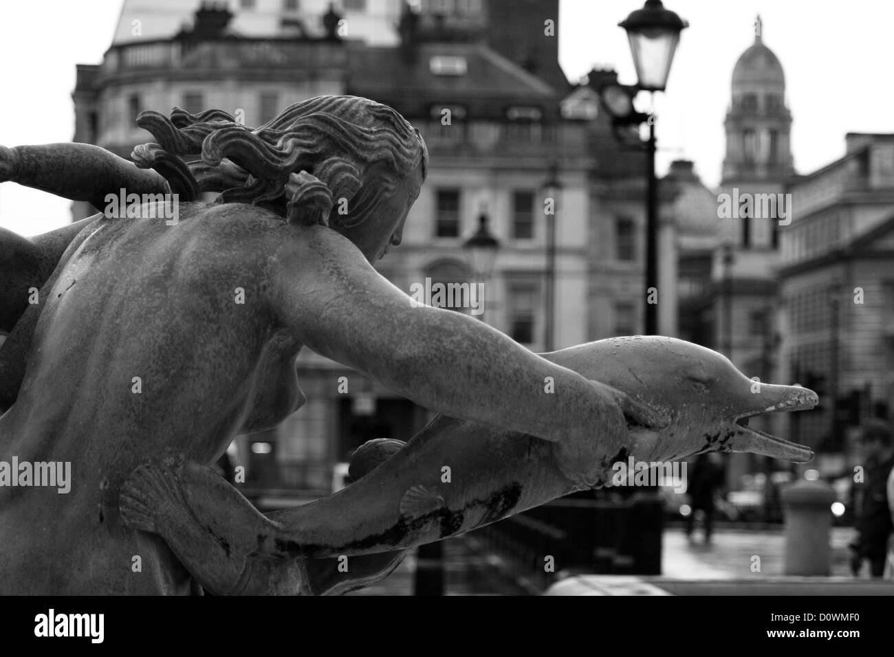Parte di una scultura d'acqua in Trafalgar Square con gli edifici circostanti in background Foto Stock