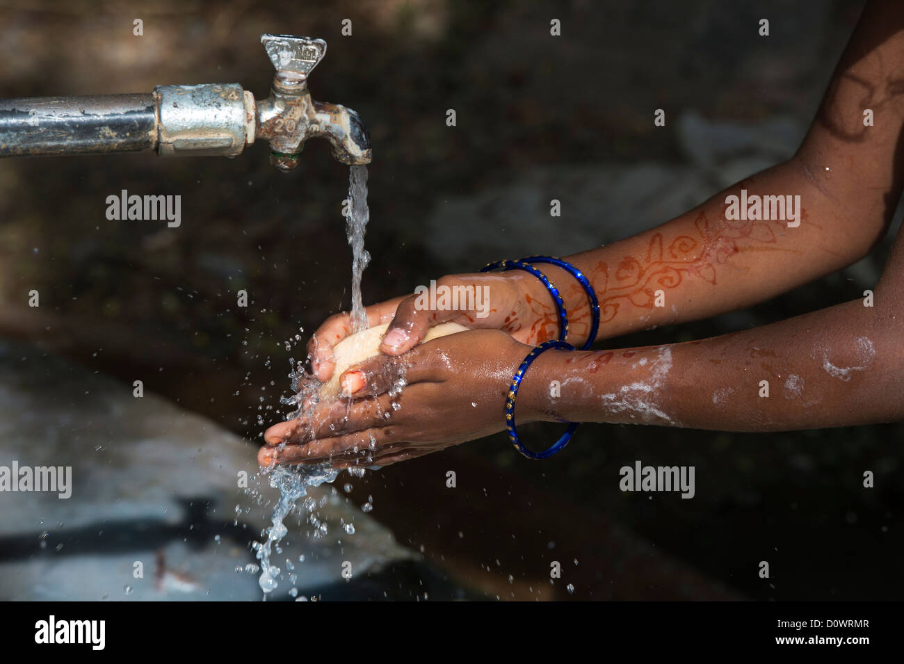 Ragazza indiana lavarsi le mani con sapone ad un comune rubinetto di acqua nelle zone rurali del villaggio indiano. Andhra Pradesh, India Foto Stock