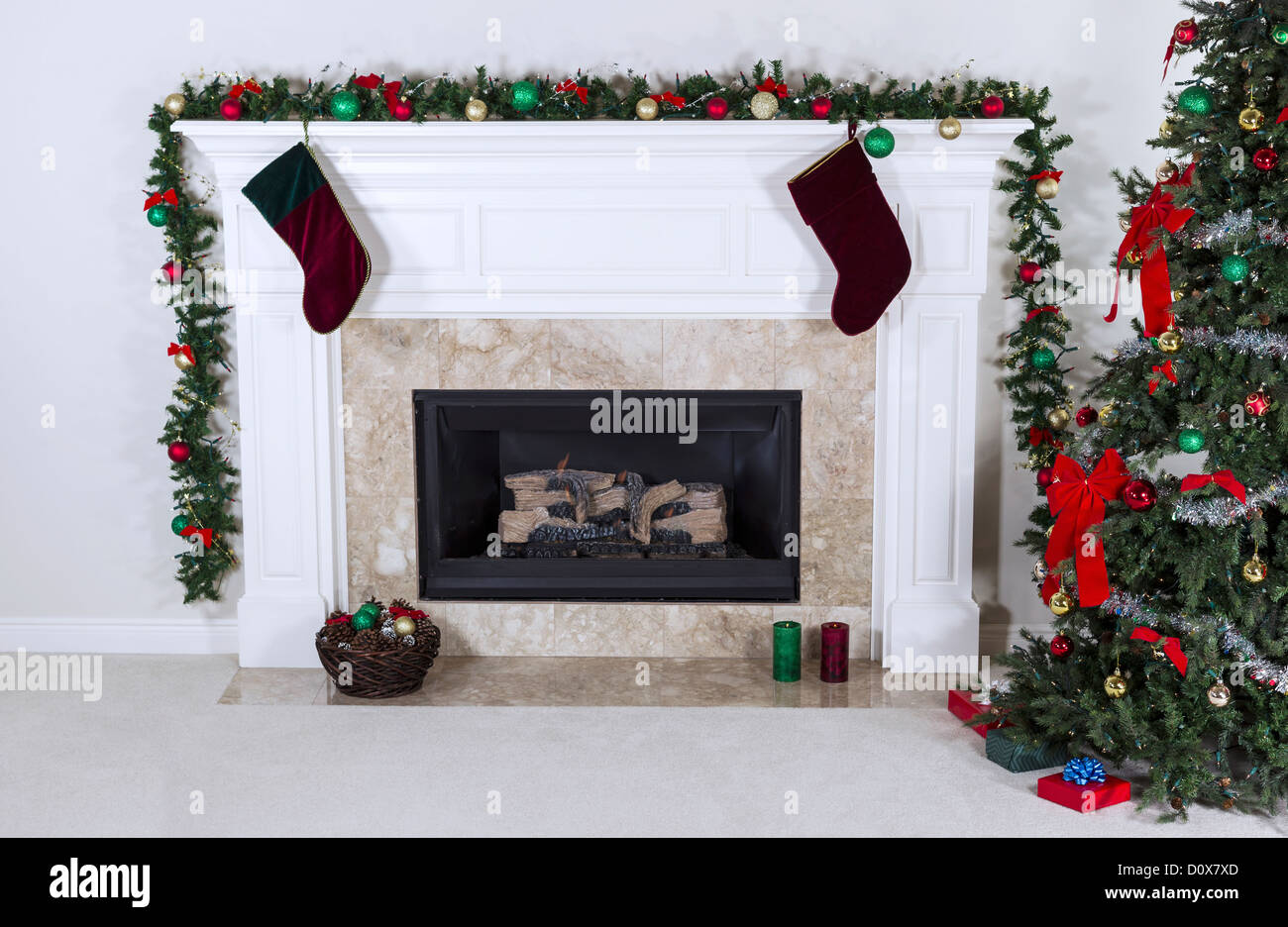 Il gas naturale camino decorato con albero, ornamenti, calze, basket e regali Foto Stock