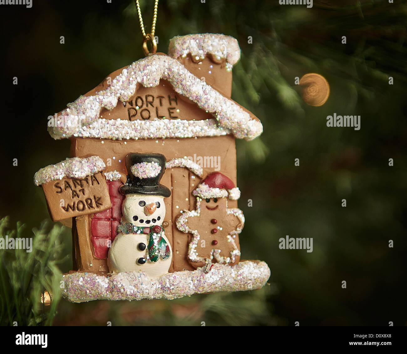 Un albero di Natale ornamento che raffigura il pupazzo di neve il pupazzo di neve e di un omino di pan di zenzero di fronte un panpepato Workshop Santa. Foto Stock