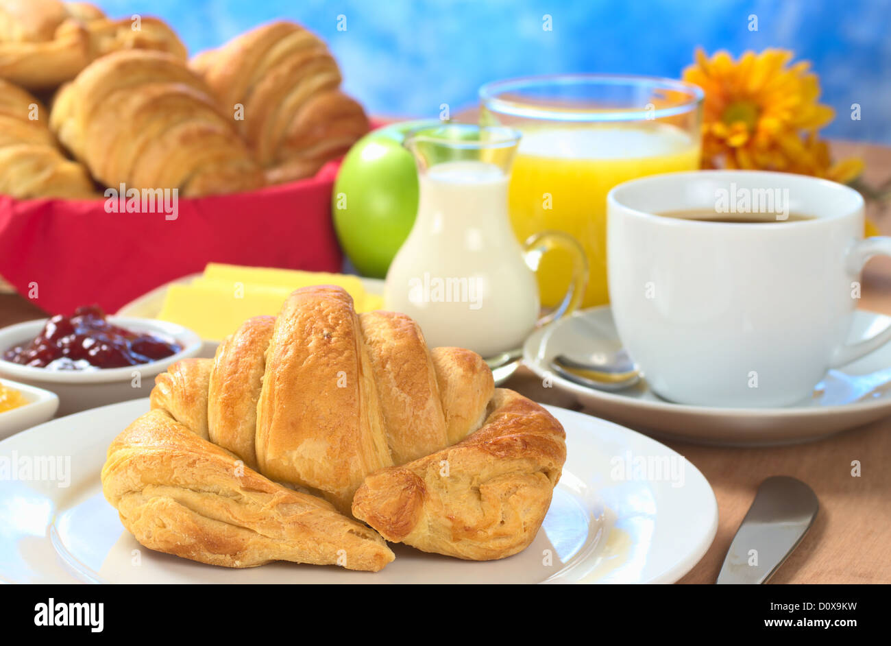 La prima colazione continentale con croissant, caffè, succo d'arancia, latte, marmellate, burro e mela verde Foto Stock