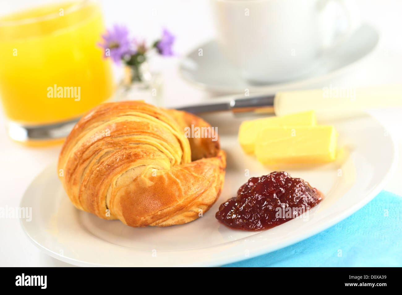 La prima colazione continentale con croissant, confettura di fragole, burro, succo d'arancia e caffè (messa a fuoco selettiva, concentrarsi sull'inceppamento) Foto Stock