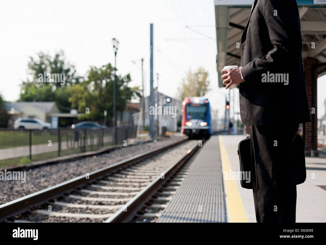 Imprenditore in attesa del treno in avvicinamento Foto Stock