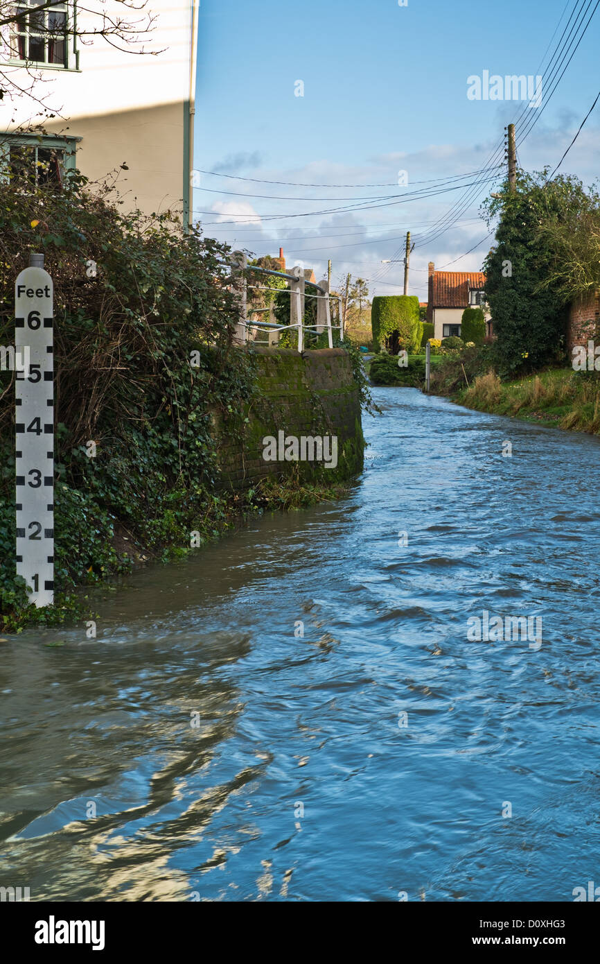 Il percorso di un fiume che scorre attraverso il villaggio di Debenham nel Suffolk. L'indicatore mostra la profondità del fiume è meno di un piede. Foto Stock