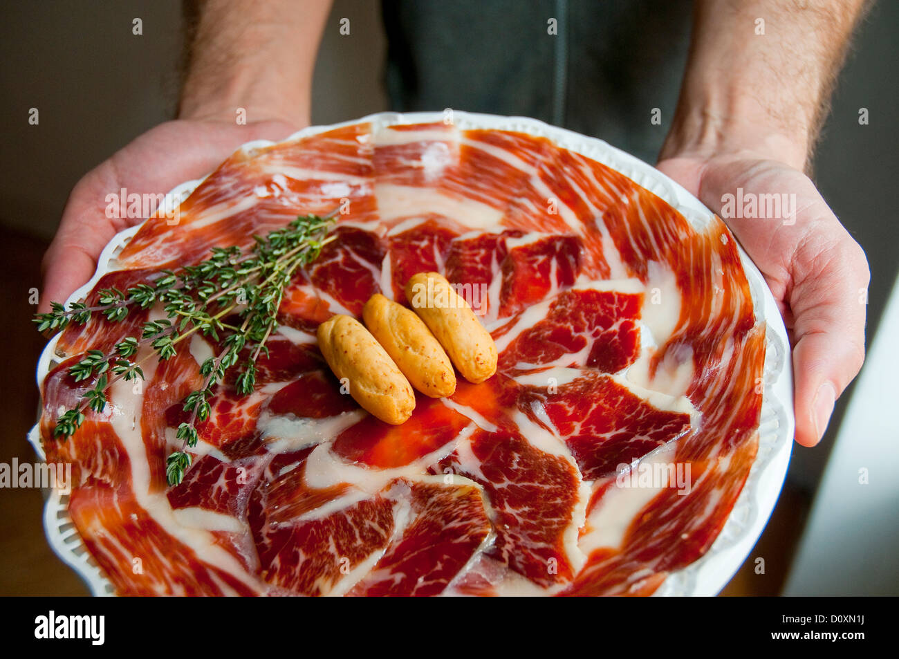 L'uomo le mani tenendo un piatto di prosciutto iberico. Foto Stock