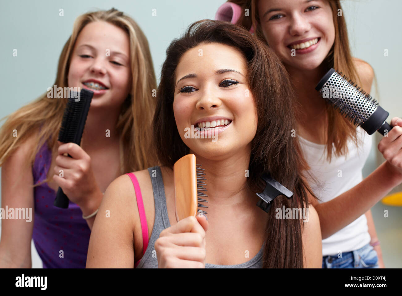 Le ragazze adolescenti cantando in spazzole per capelli Foto Stock