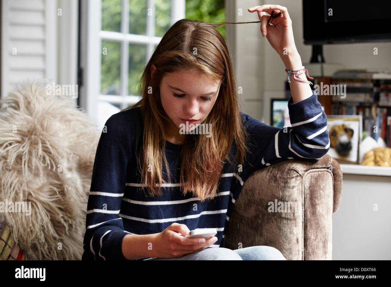 Guardando adolescenti al cellulare e a giocare con i suoi capelli Foto Stock