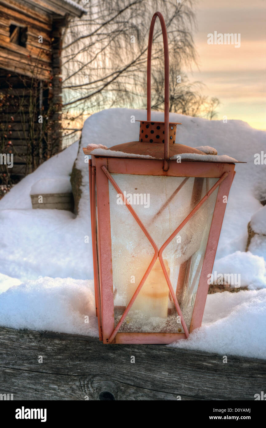Lanterna rustico in nevoso inverno sera di fronte a un vecchio fienile in legno Foto Stock