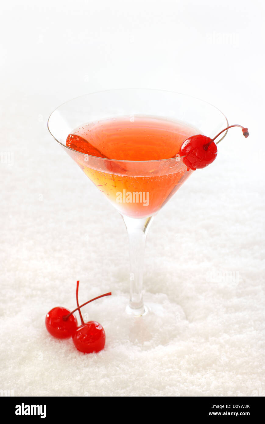 La ciliegia il cocktail in una coppetta Martini decorate con ciliegie al maraschino, sulla neve. Foto Stock