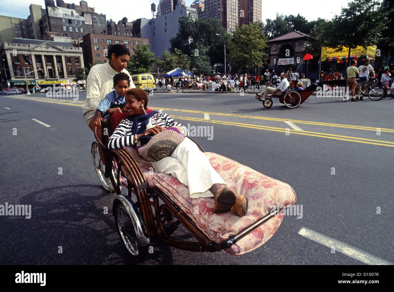 Circa 1992 - Una famiglia prende una spin su "Chaise' ad un trasporto alternativo Festival in Union Square Park. Foto Stock