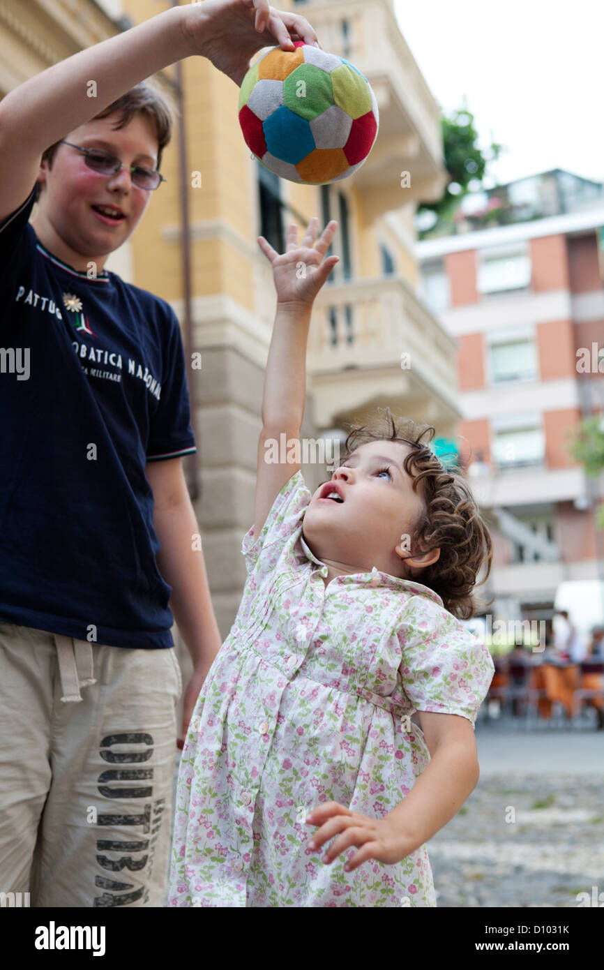Bambini che giocano con una morbida palla in una città italiana square Foto Stock