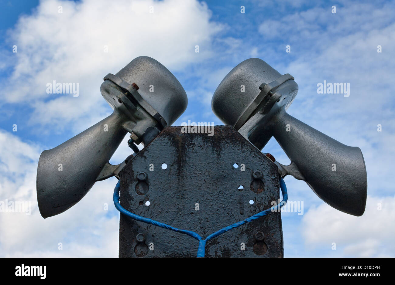 Una coppia di altoparlante megafoni montata in cima ad un palo alto insieme contro un nuvoloso cielo blu. Foto Stock