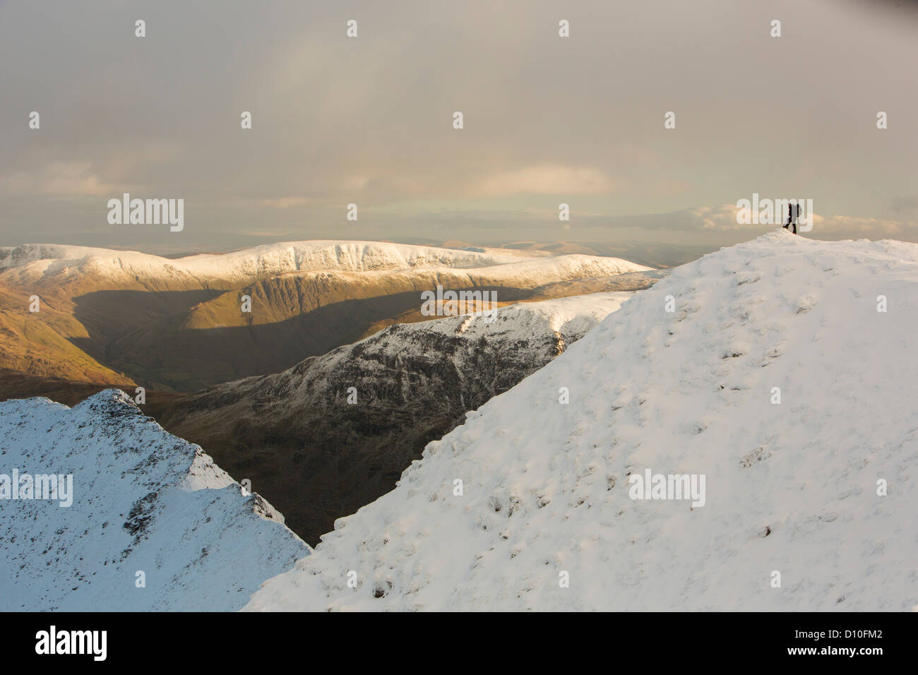 Un camminatore su Helvellyn nella neve, Lake District, UK, guardando verso il basso verso il bordo di estensione Foto Stock