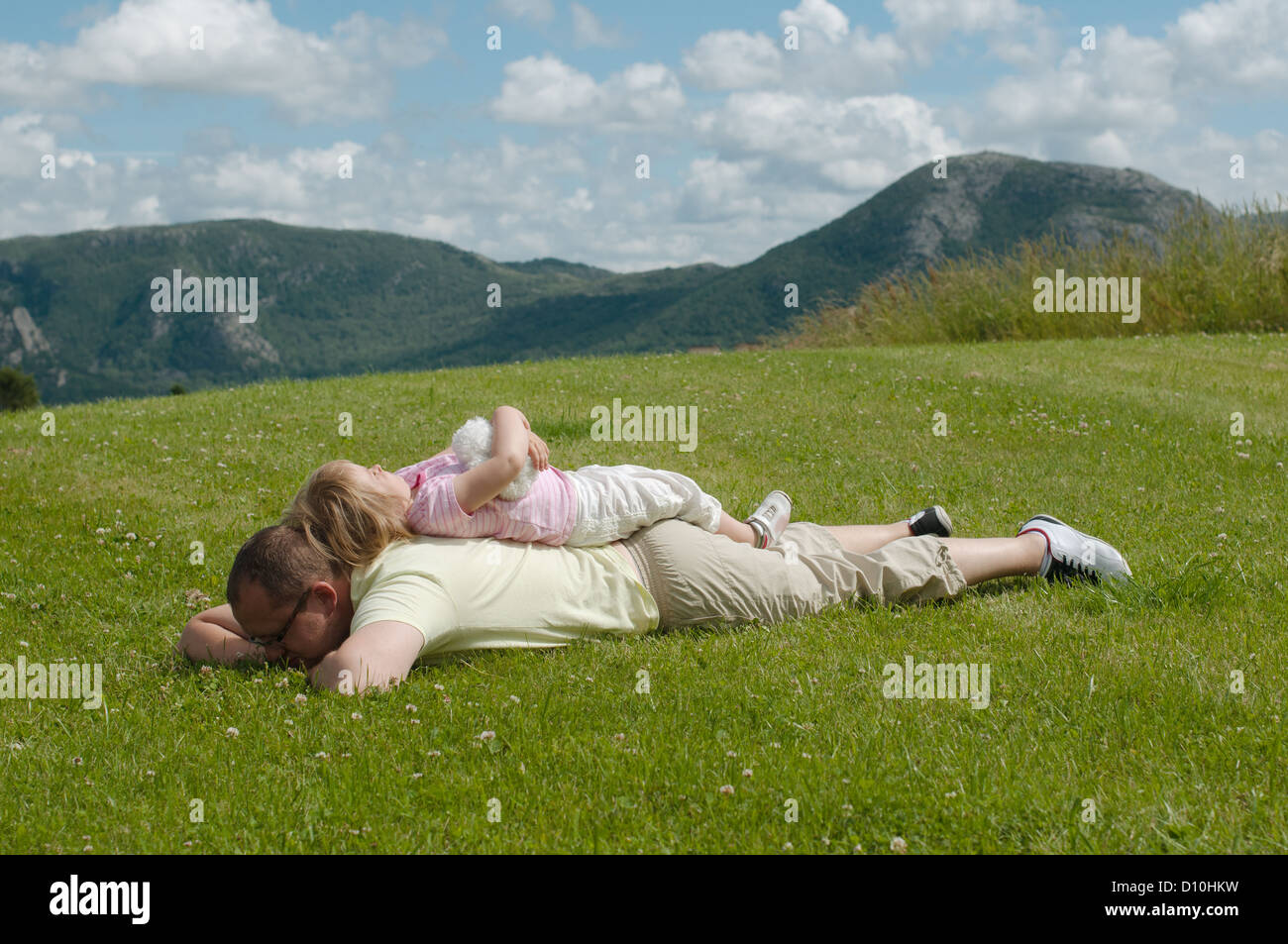 Padre e figlio sdraiati sull'erba sulle colline sullo sfondo Foto Stock