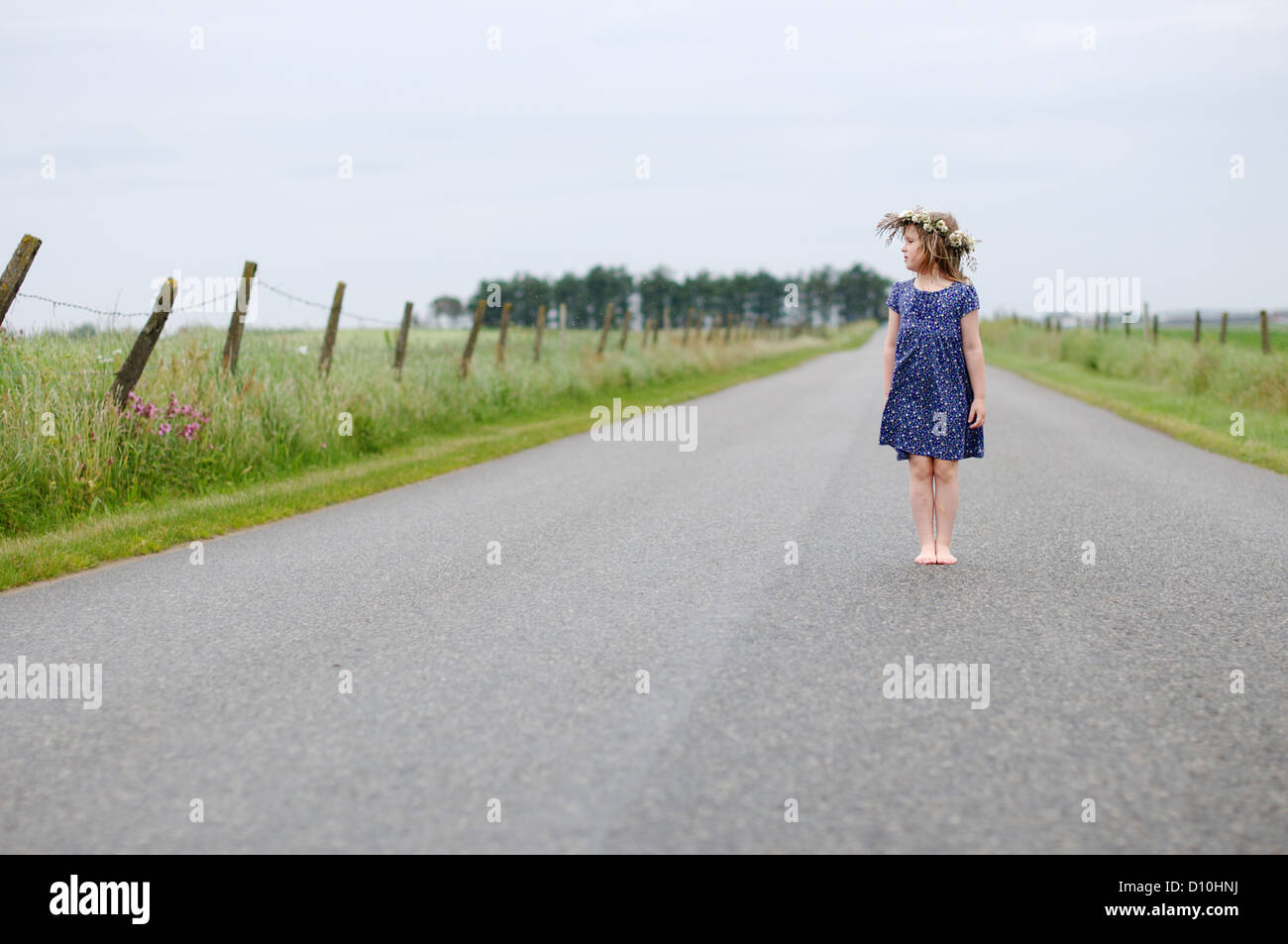 Una ragazza che indossa vestito blu con una ghirlanda attorno alla sua testa sul campo di grano Foto Stock