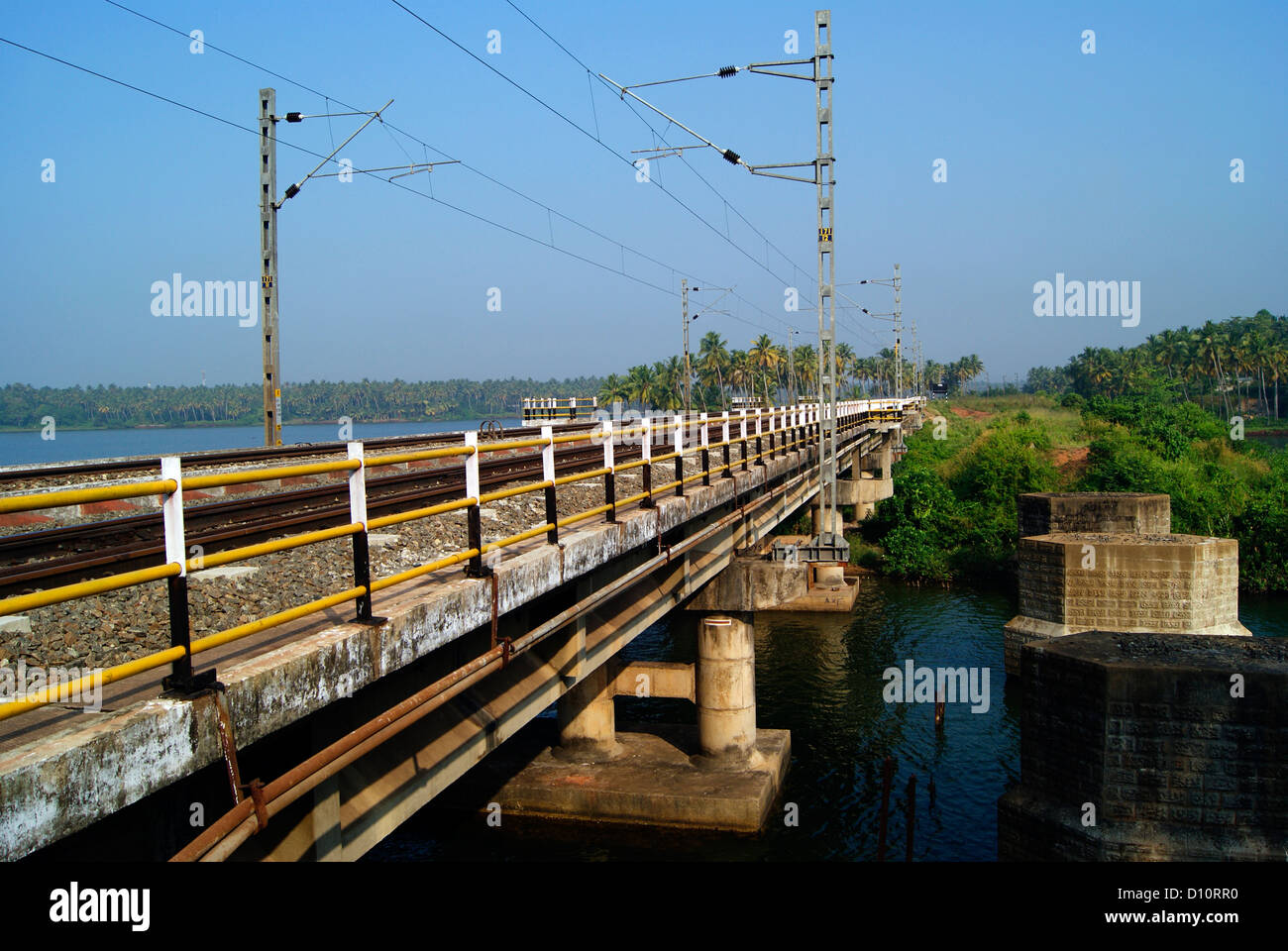 India calcestruzzo ponte ferroviario e la ferrovia elettrica Post sullo sfondo del Kerala Backwaters Foto Stock