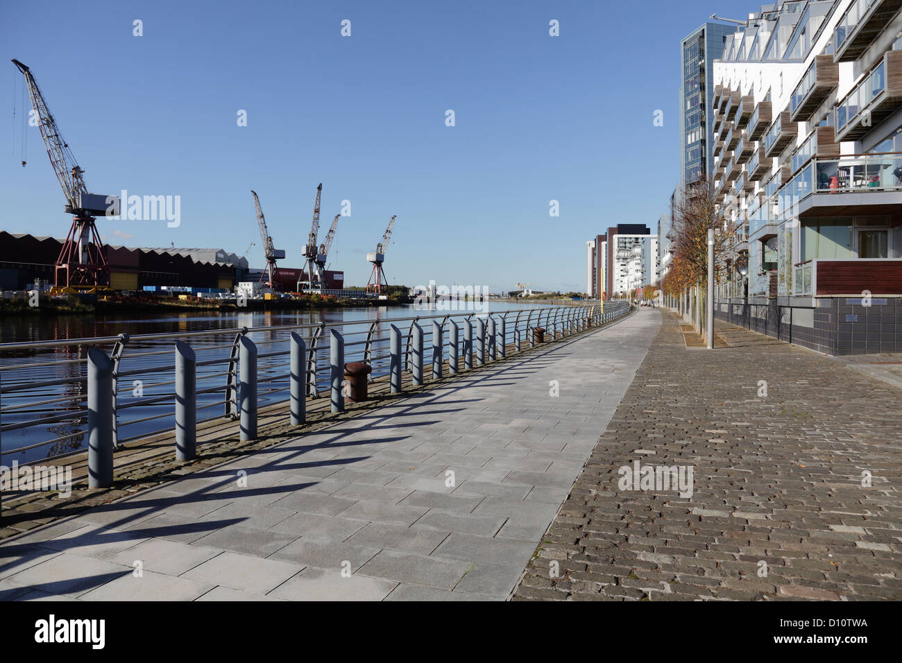 Vista Ovest lungo il fiume Clyde a BAE Systems cantiere, a sinistra e a Glasgow Harbour alloggiamento privato, diritto, Glasgow, Scotland, Regno Unito Foto Stock