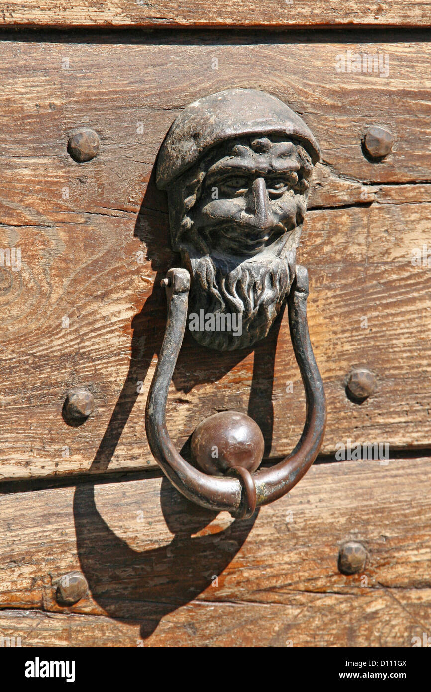 Porta di ferro battenti con una faccia a bussare alla porta di legno Foto Stock