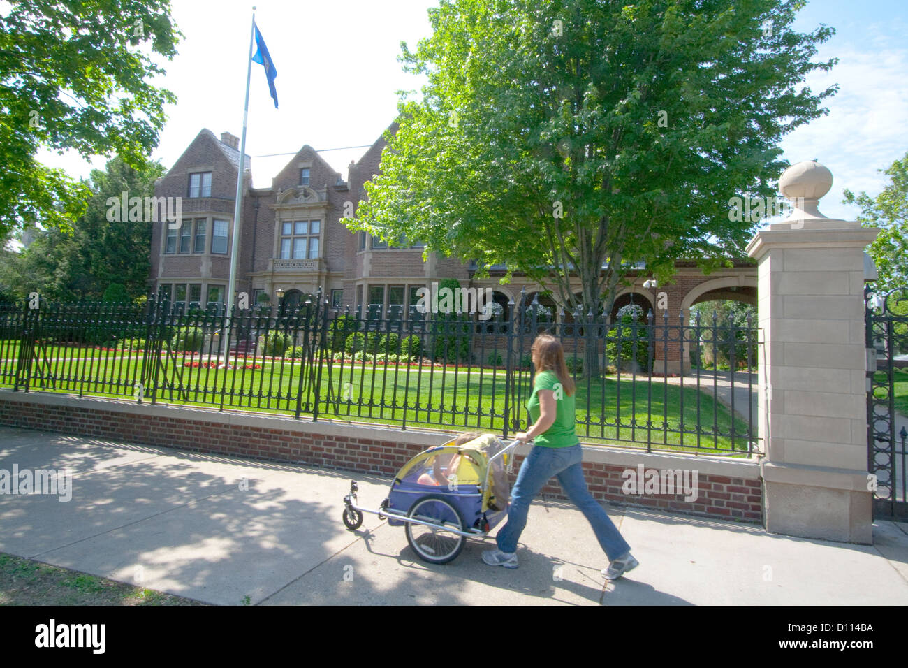Donna età 30 spingendo i suoi due bambini in un passeggino nella parte anteriore della residenza del governatore Mansion. St Paul Minnesota MN USA Foto Stock