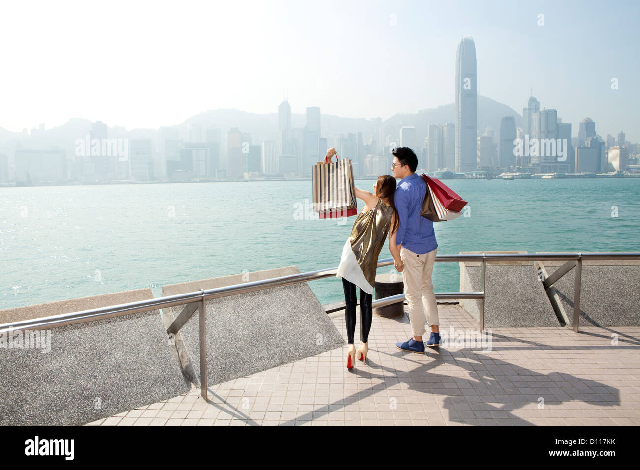 Moda giovane coppia con shopping bags godendo il porto di Victoria e di Hong Kong Foto Stock