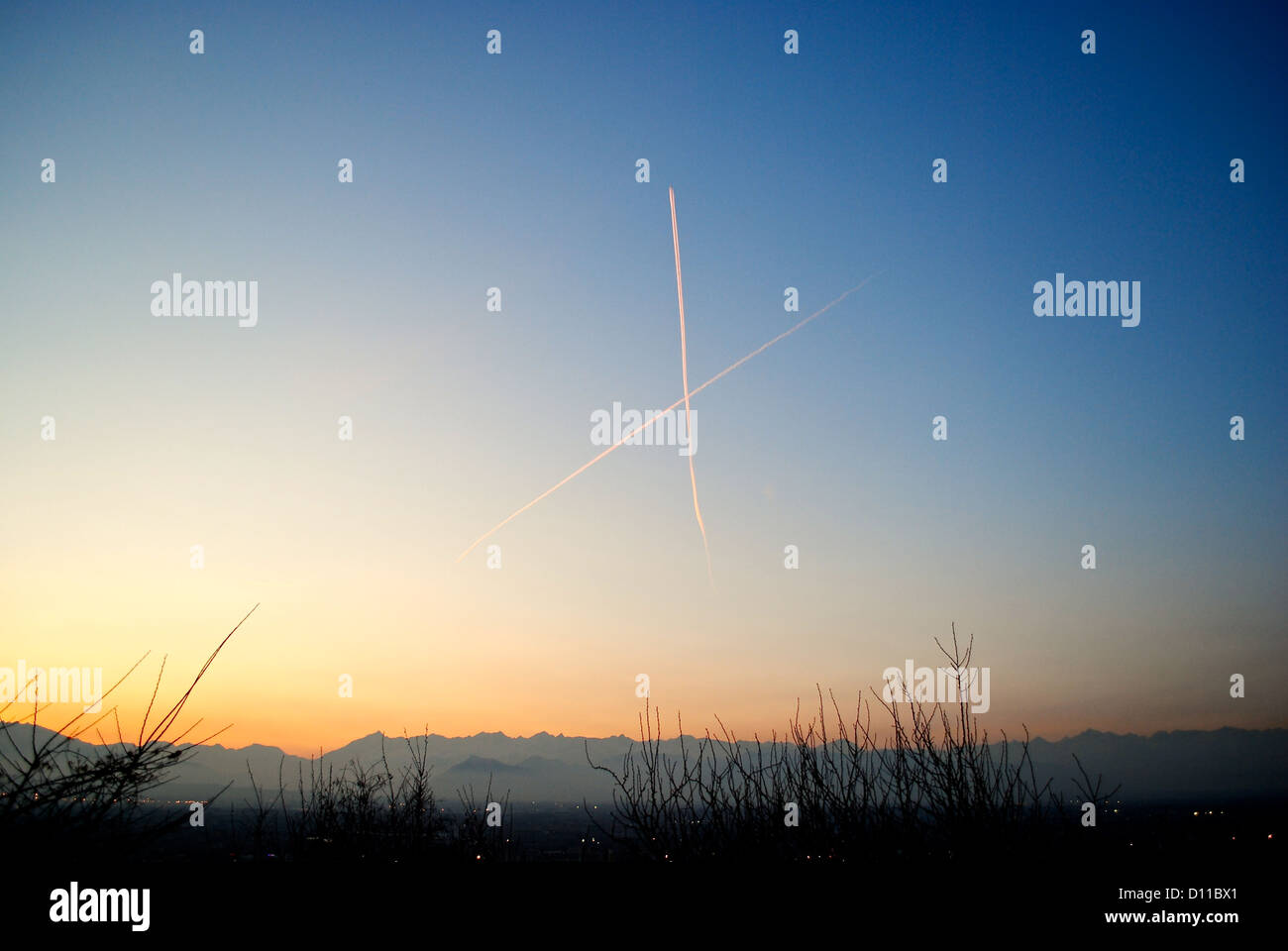 Aeromobile percorsi che attraversano ogni altri su Torino skyes al tramonto con lo sfondo delle Alpi. Foto Stock