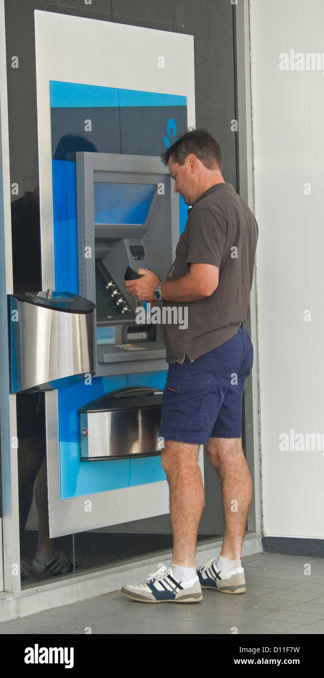 Uomo in abbigliamento casual con automatic teller machine - ATM - al di fuori di una banca Foto Stock