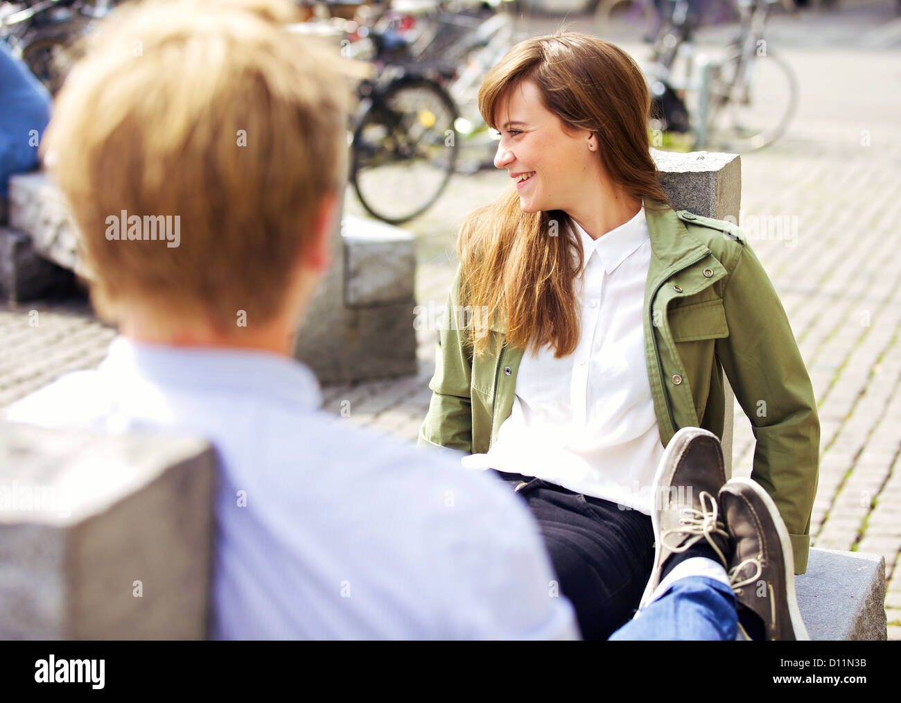 Rilassante attraente donna seduta su una panchina nel parco insieme con il suo fidanzato godendo della piacevole mattinata Foto Stock