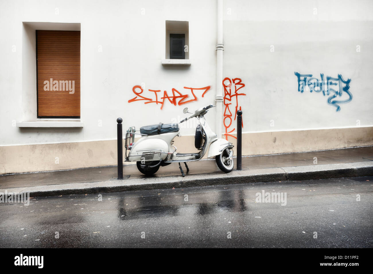Parigi, Francia: Vespa scooter parcheggiato su una strada di città sotto la pioggia Foto Stock