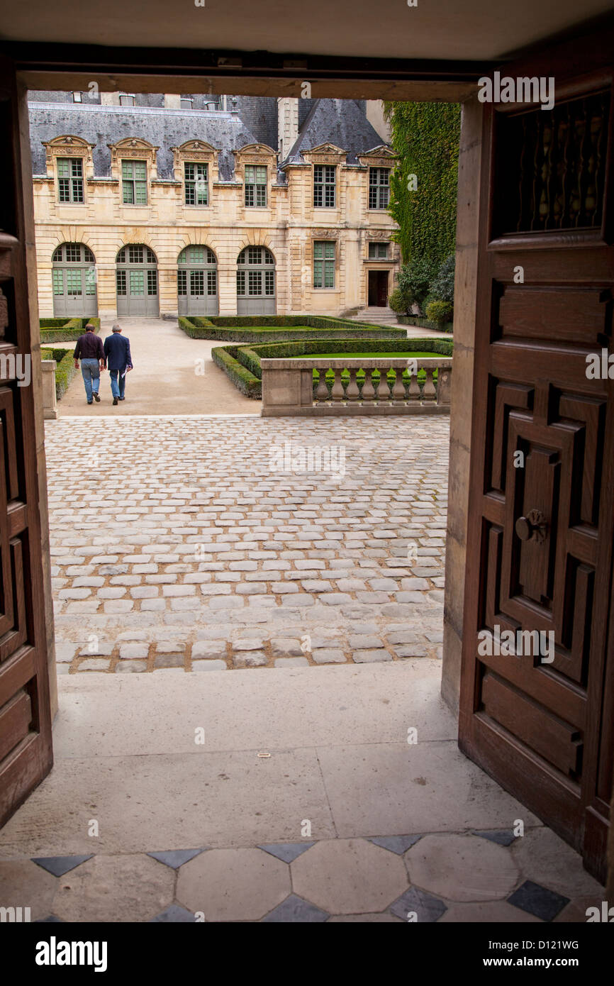 Due uomini a piedi attraverso il giardino dell'Hotel de Sully nel quartiere di Marais, Parigi Francia Foto Stock