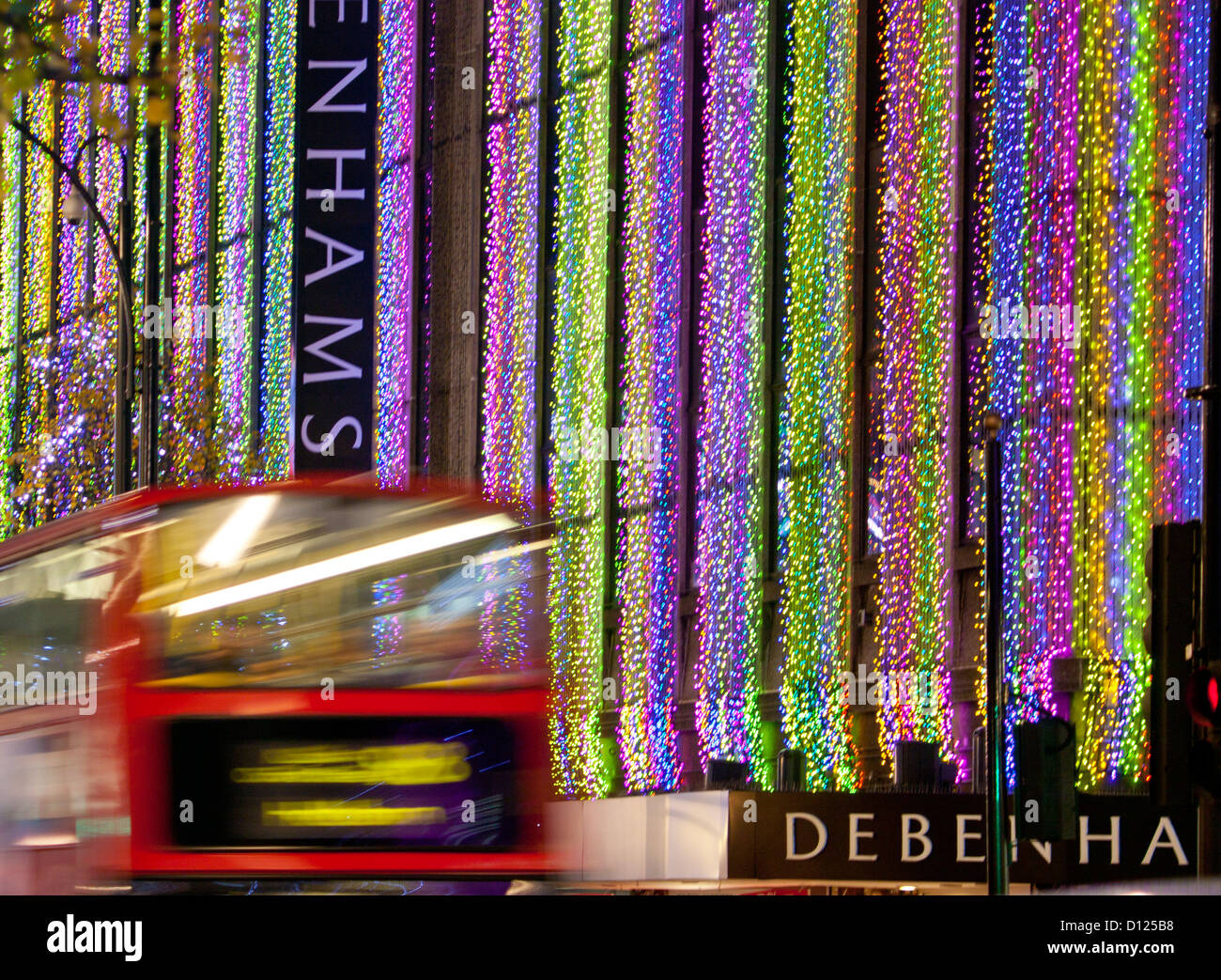 Red Bus londinese passando Debenhams department store in Oxford Street con le luci di Natale di notte Londra Inghilterra REGNO UNITO Foto Stock