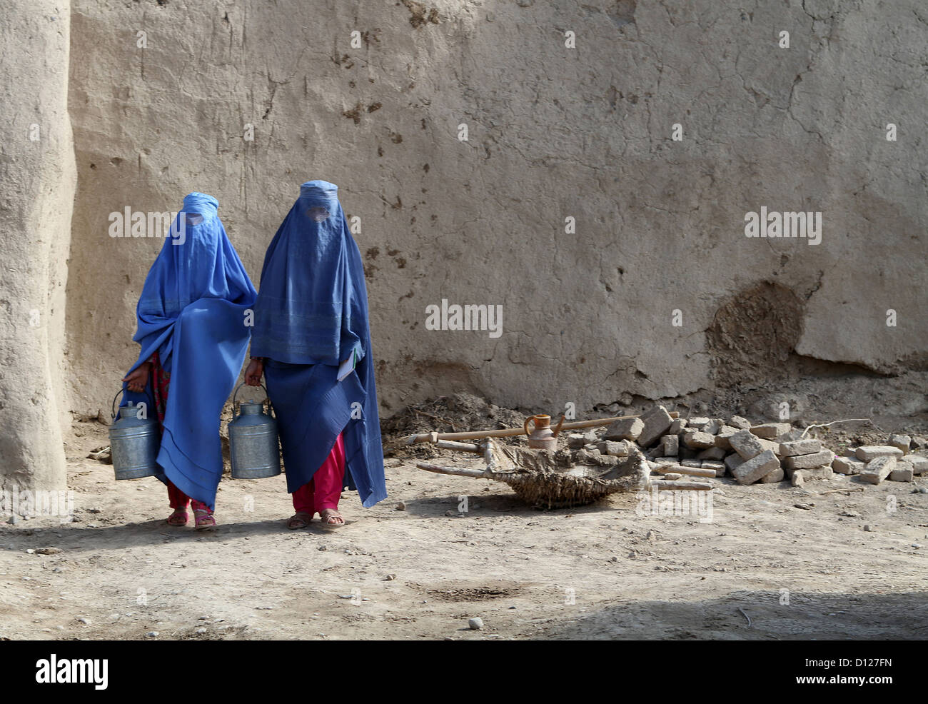 Le donne afghane indossando il tradizionale pieno di copertura del corpo chiamato Burqa trasportare secchi del latte da un USAID lavorazione del latte Ottobre 22, 2012 in Jebul Saraj, Afghanistan Foto Stock