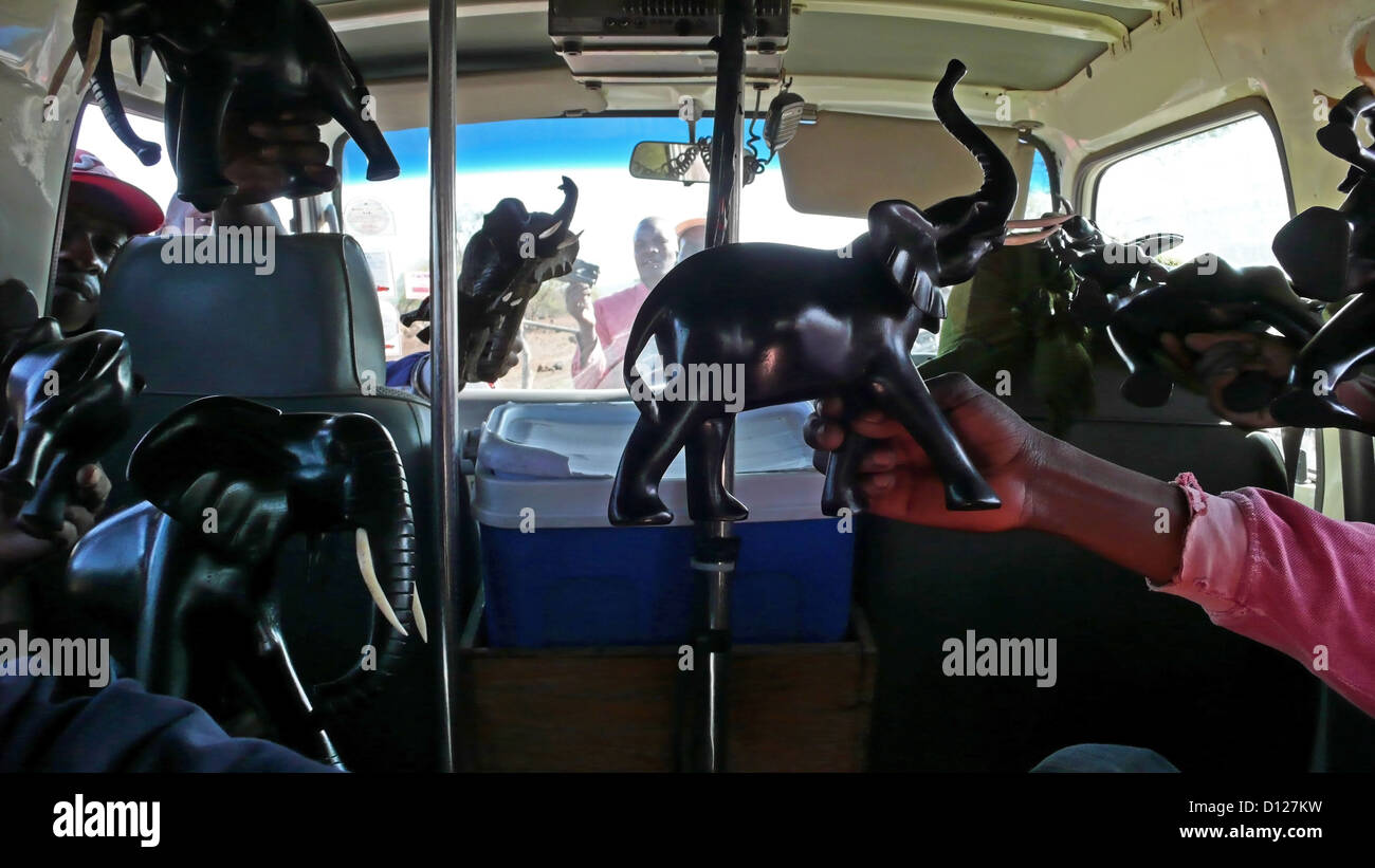 La gente del posto cerca di vendere sculture in legno ai turisti in un mini bus, Tsavo East National Park, Kenya, Africa orientale. 6/2/2009. Fotografia: Stuart Boulton Foto Stock