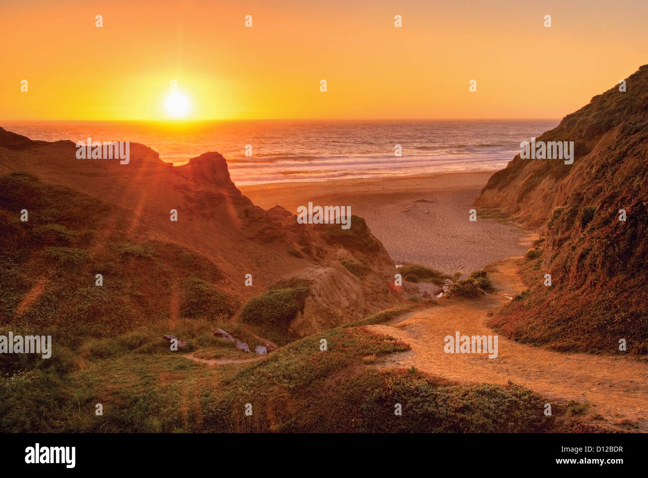 California arancione tramonto sull'oceano con il sentiero verso il basso per una spiaggia; California Stati Uniti d'America Foto Stock