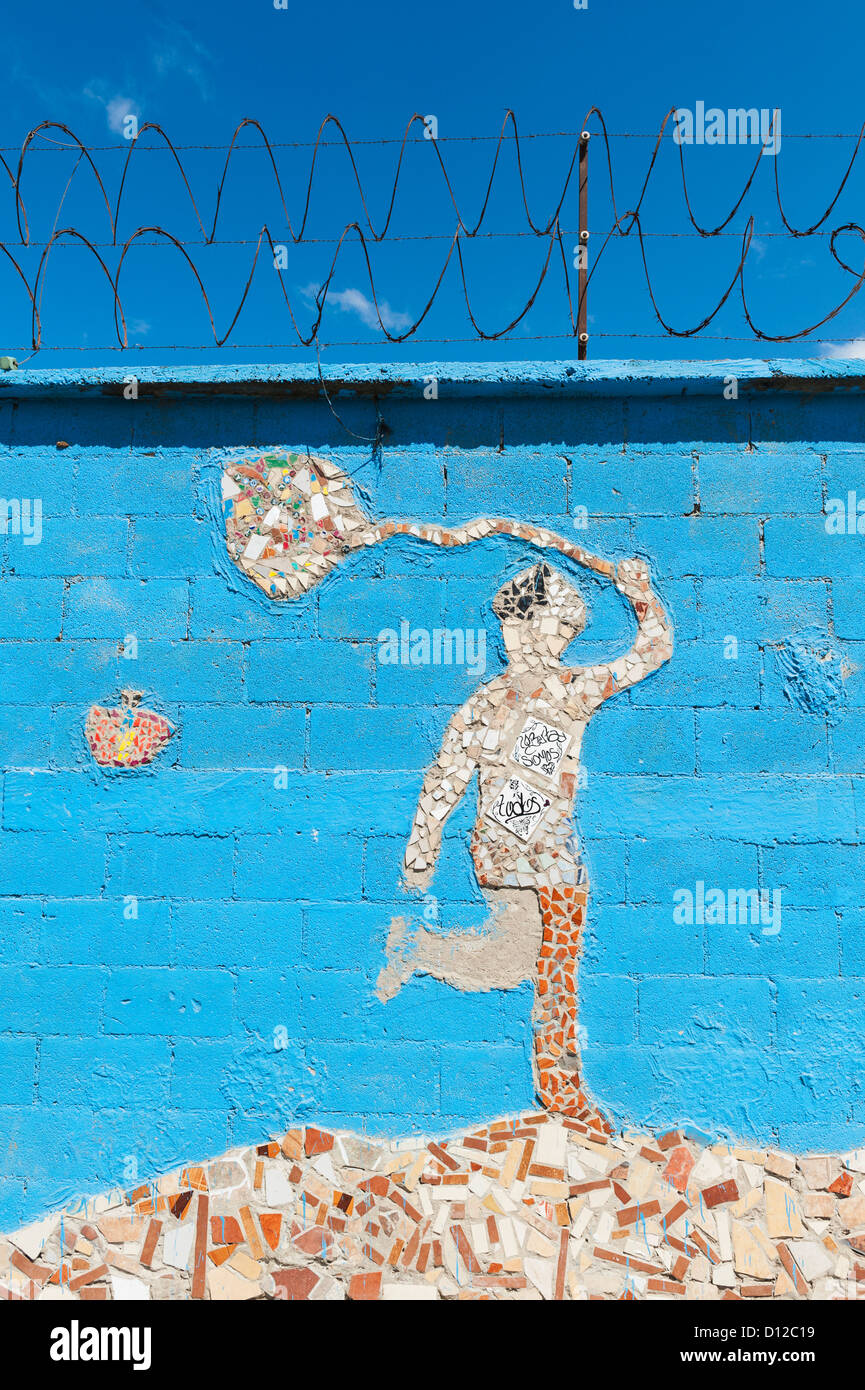 Un mosaico di una figura umana tenendo un netto e una farfalla su una parete blu; Guatemala City Guatemala Foto Stock