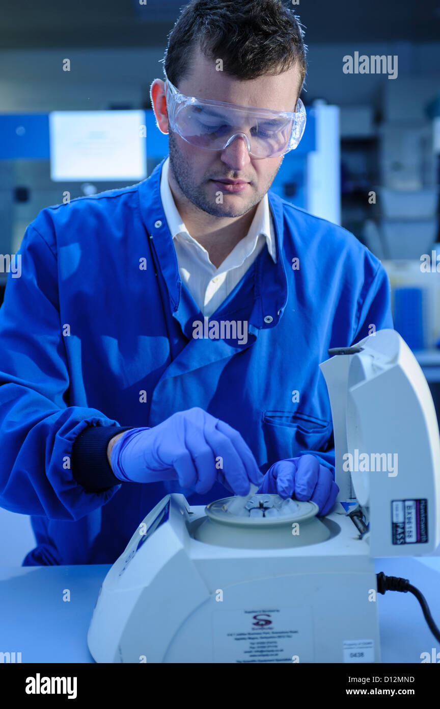 Scienziato campioni carichi in una centrifuga nel laboratorio di scienze Foto Stock