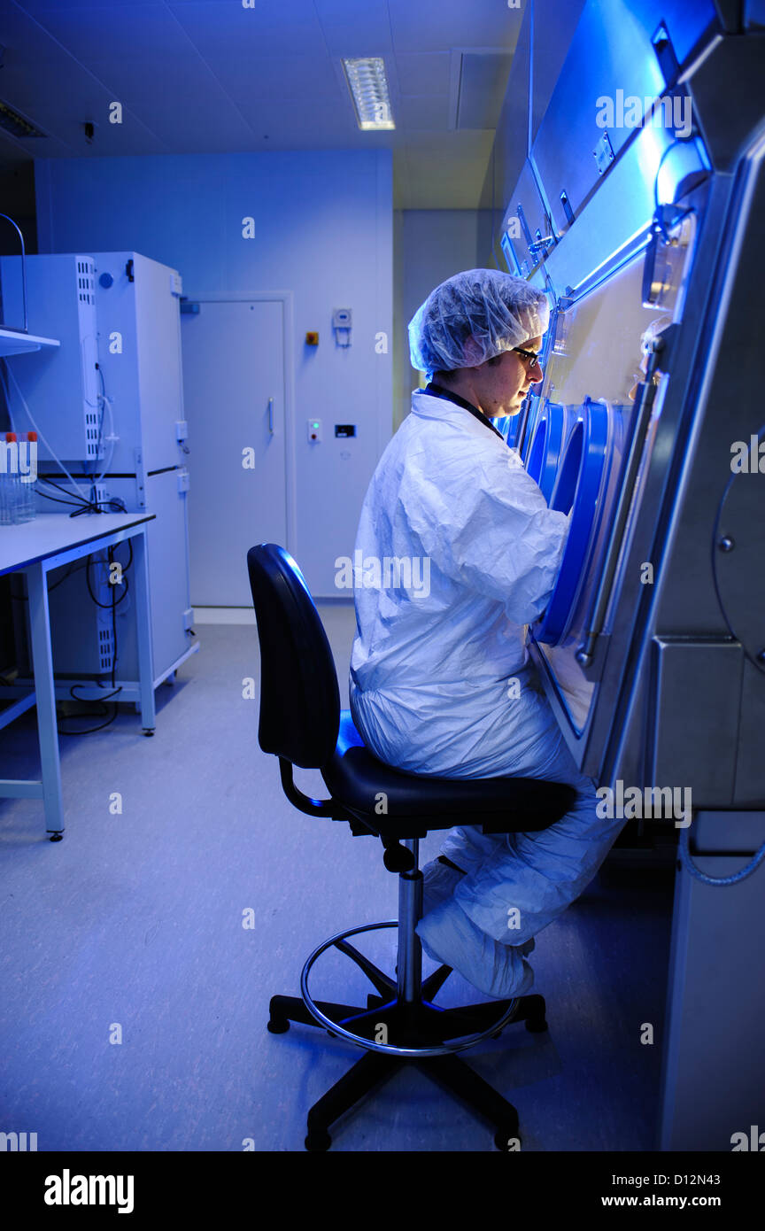 Scienziato bianco da indossare tuta sterile sigillato in opere di laboratorio a sterile sigillata sotto cappa su theraputics cellulare Foto Stock