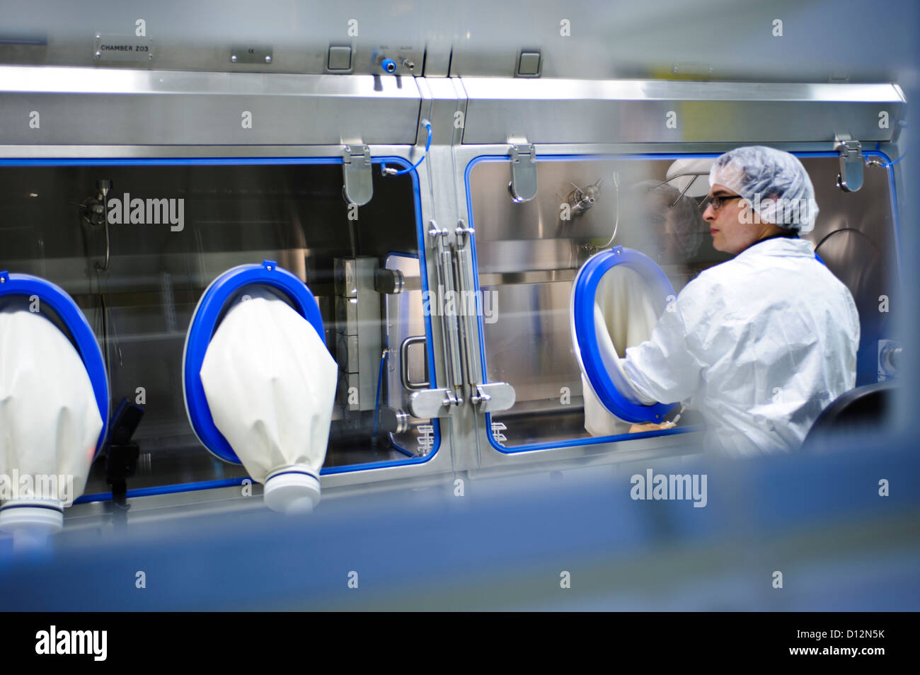 Scienziato bianco da indossare tuta sterile sigillato in opere di laboratorio a sterile sigillata sotto cappa su theraputics cellulare Foto Stock