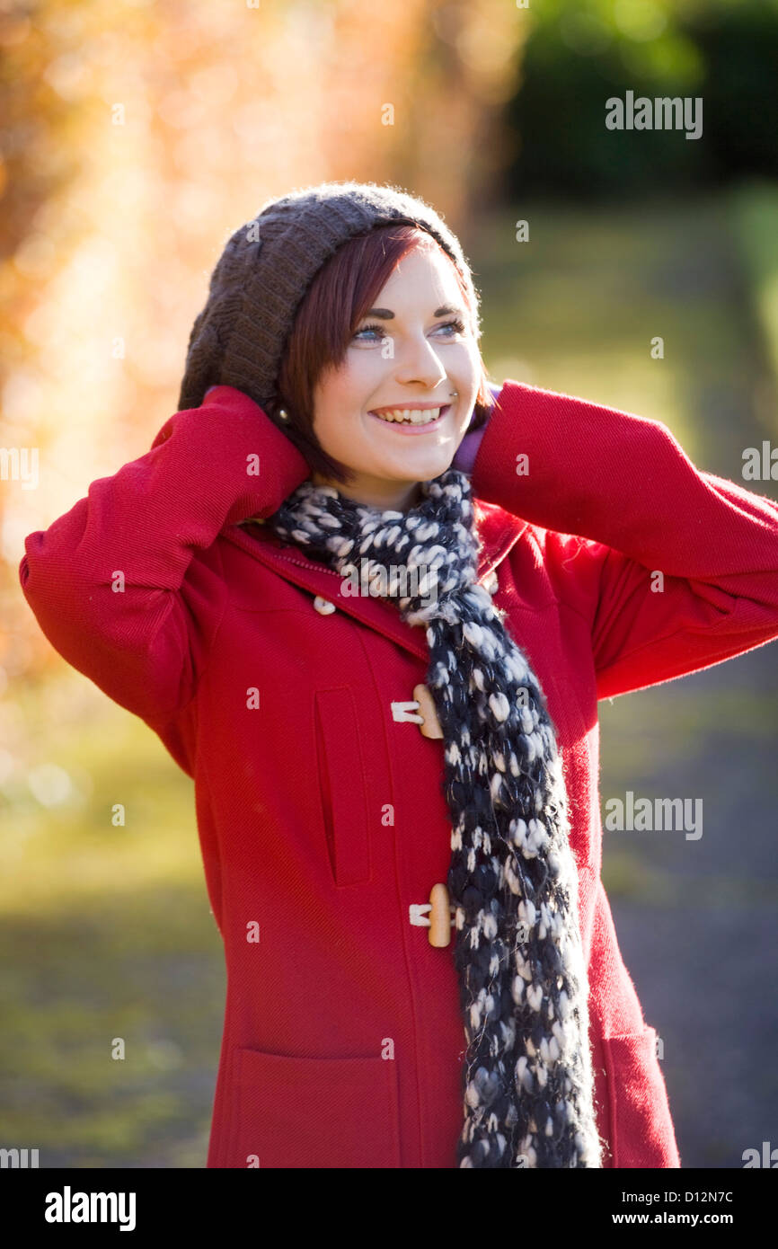 Giovane donna che indossa un cappotto rosso in un parco in Scozia. Foto Stock