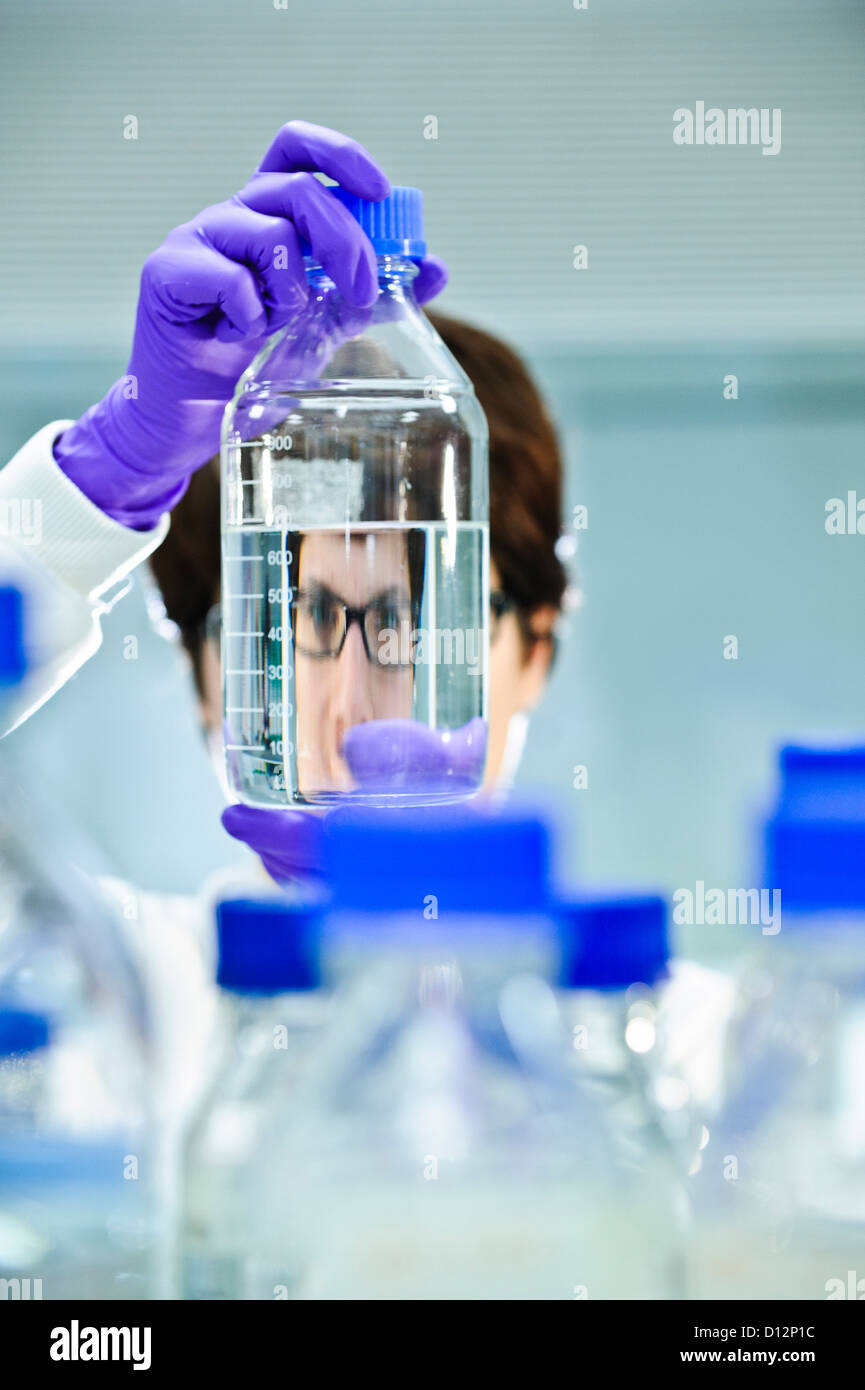 Giovani donne scienziato in laboratorio di scienze con in mano un bicchiere di campioni jar Foto Stock